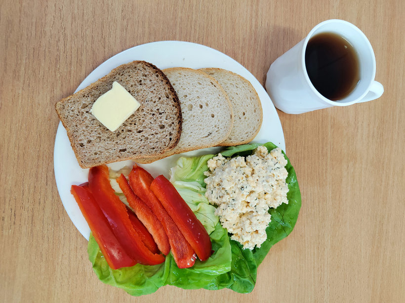 Na zdjęciu znajduje się: Herbata czarna ekspresowa z cytryną Cateringowa, Chleb mieszany pszenno-żytni, Chleb Graham, Masło extra 82%, Pasta z jaj z koperkiem, Papryka świeża, ​​​​​​​Sałata zielona